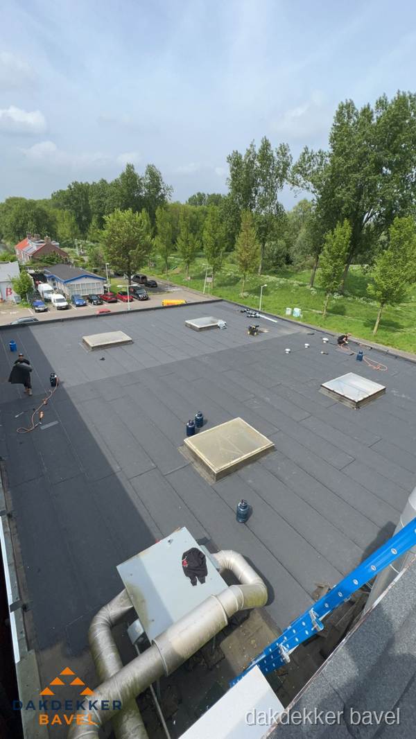 Dakdekker aan het werk op groot plat dak met bitumen in Bavel Dakdekker aan het werk op groot plat dak met bitumen in Bavel
