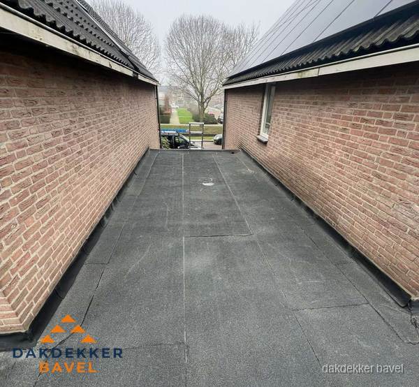 Plat dak met bitumen dakbedekking tussen bakstenen muren in Bavel Plat dak met bitumen dakbedekking tussen bakstenen muren in Bavel