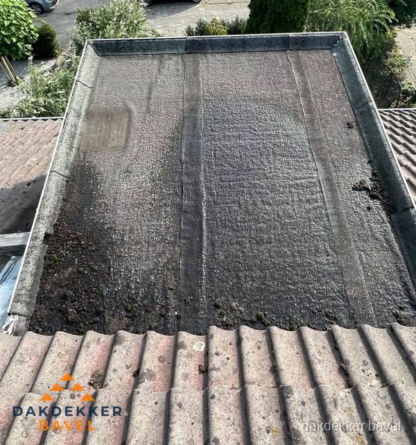 Verouderd plat dak met bitumen en slijtage voor lekkage inspectie in Bavel Verouderd plat dak met bitumen en slijtage voor lekkage inspectie in Bavel