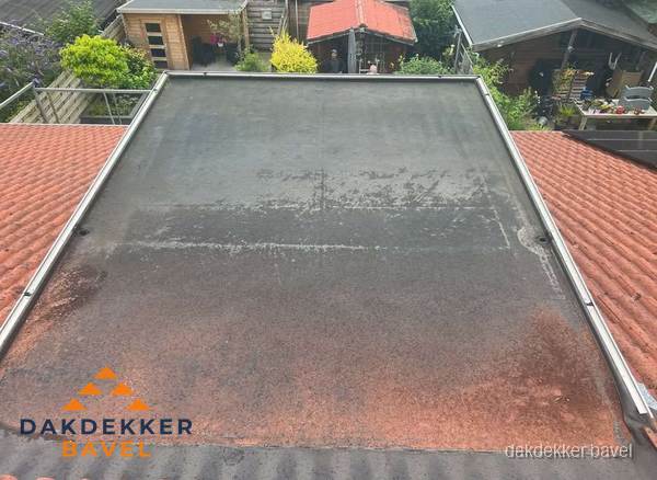 Verouderd plat dak met slijtage tussen schuine daken in Bavel Verouderd plat dak met slijtage tussen schuine daken in Bavel